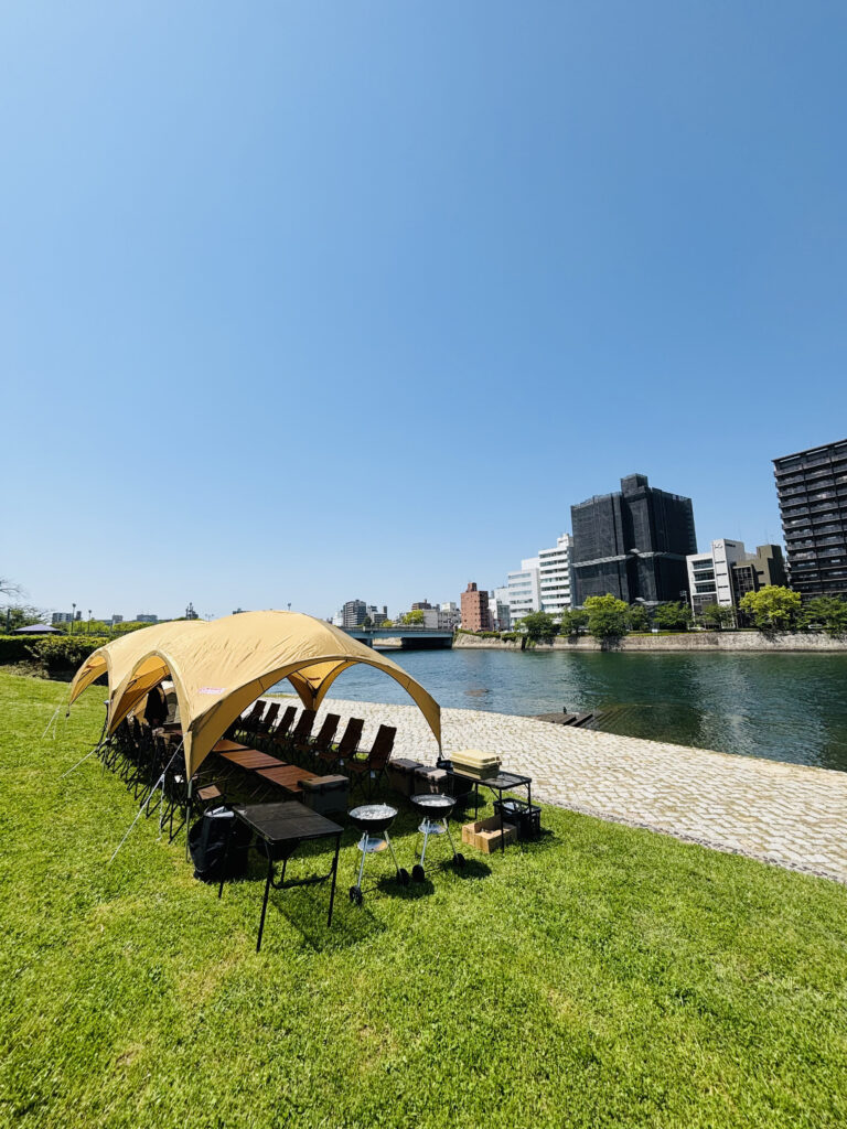 晴れた日、広島の川辺の公園でBBQレンタル設営